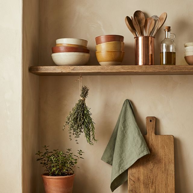 Dettaglio cucina Japandi con mensola in rovere, ciotole in ceramica, portautensili in rame, erbe secche e tagliere artigianale